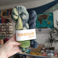 Full skein and mini skein sock yarn set with hand dyed variegated yarn in sage green, cream and blue-grey shades paired with a smoky blue mini skein.