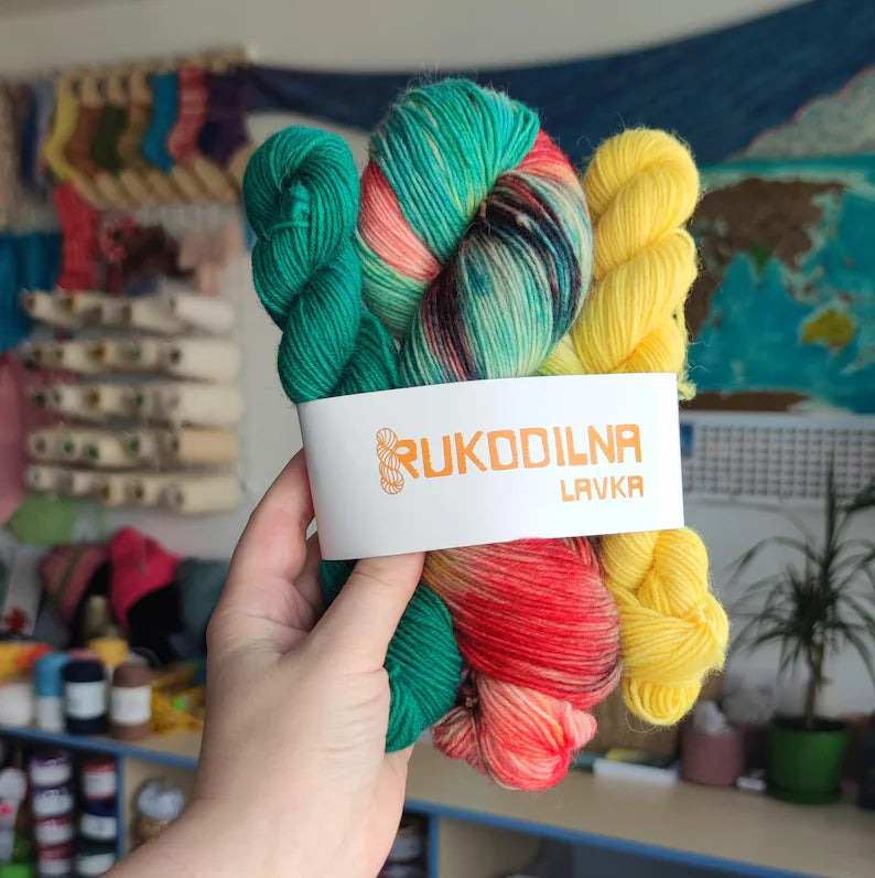 Hand dyed Christmas sock yarn set featuring a variegated skein in red, green, yellow and turquoise shades paired with coordinating green and yellow mini skeins for festive holiday knitting and Christmas socks.