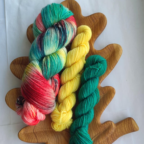 Hand dyed Christmas sock yarn set featuring a variegated skein in red, green, yellow and turquoise shades paired with coordinating green and yellow mini skeins for festive holiday knitting and Christmas socks.