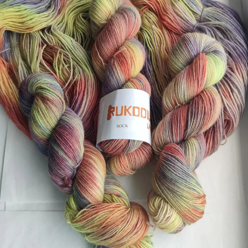 Hand dyed sock yarn in grape purple, lavender, blush pink, olive green and golden tones inspired by autumn vineyards.