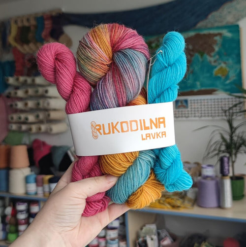 Hand dyed sock yarn set featuring a colorful variegated skein with pink, gold, turquoise and lavender shades paired with bright turquoise and berry pink mini skeins.