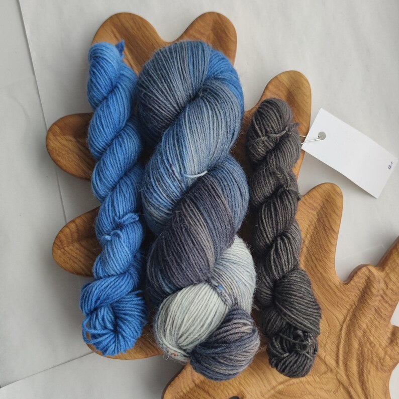 Hand dyed sock yarn set with blue gray variegated skein and two coordinating mini skeins in smoky gray and denim blue tones for knitting socks and shawls.
