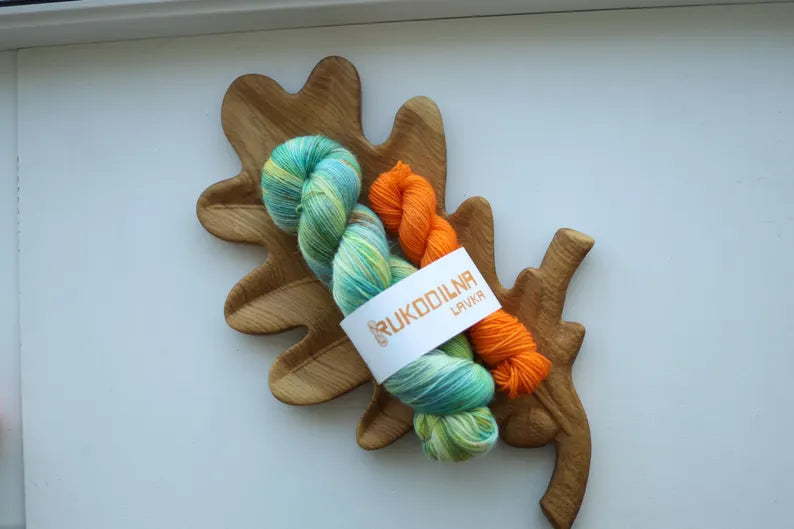 Hand dyed sock yarn set with one mint variegated 100g skein and one bright orange 20g mini skein on a wooden tray.