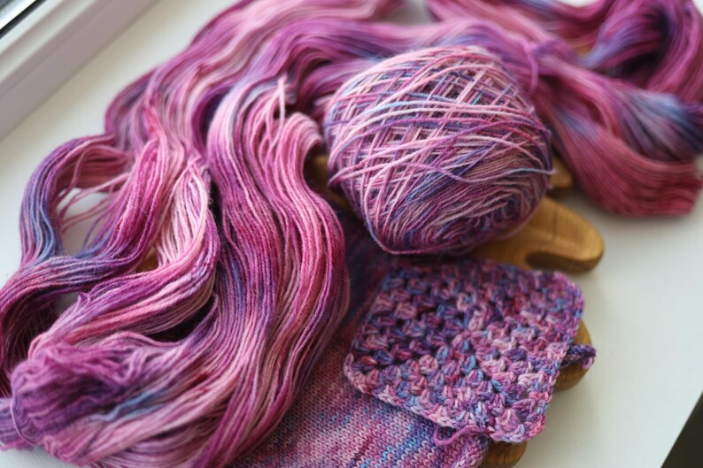 Hand dyed lilac sock yarn in soft purple, blush pink and lavender with delicate blue speckles, fingering weight wool nylon knitting yarn.