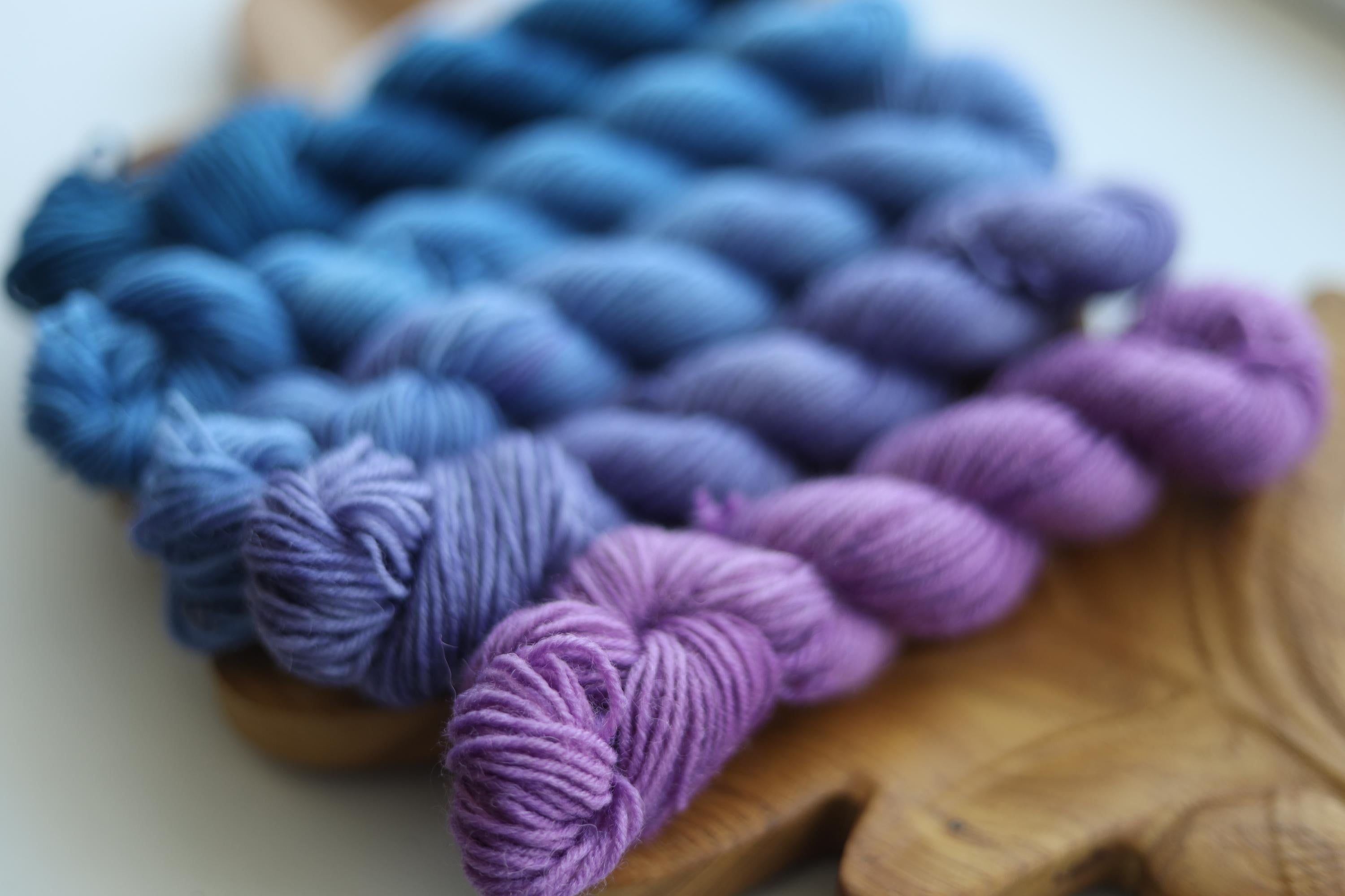 Hand dyed mini skein set with five blue and purple fingering weight sock yarn mini skeins for knitting and crochet colorwork.