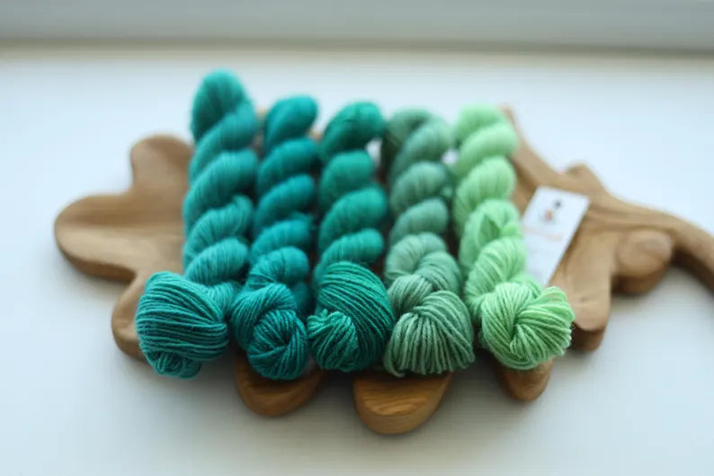 Hand dyed green mini skein set with five fingering weight sock yarn mini skeins in teal, forest green and mint shades for knitting and crochet.