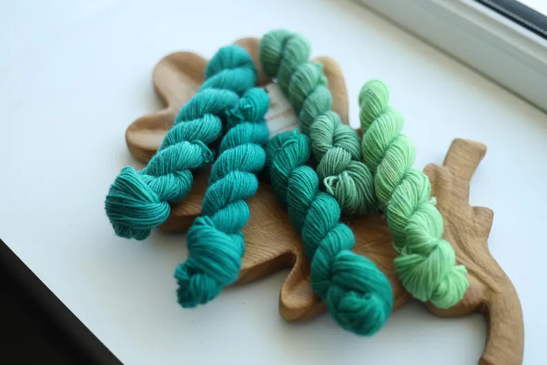 Hand dyed green mini skein set with five fingering weight sock yarn mini skeins in teal, forest green and mint shades for knitting and crochet.