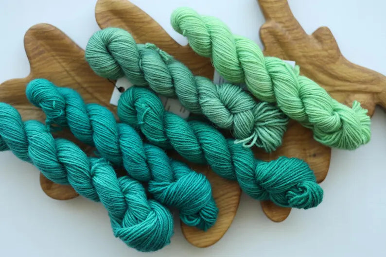 Hand dyed green mini skein set with five fingering weight sock yarn mini skeins in teal, forest green and mint shades for knitting and crochet.