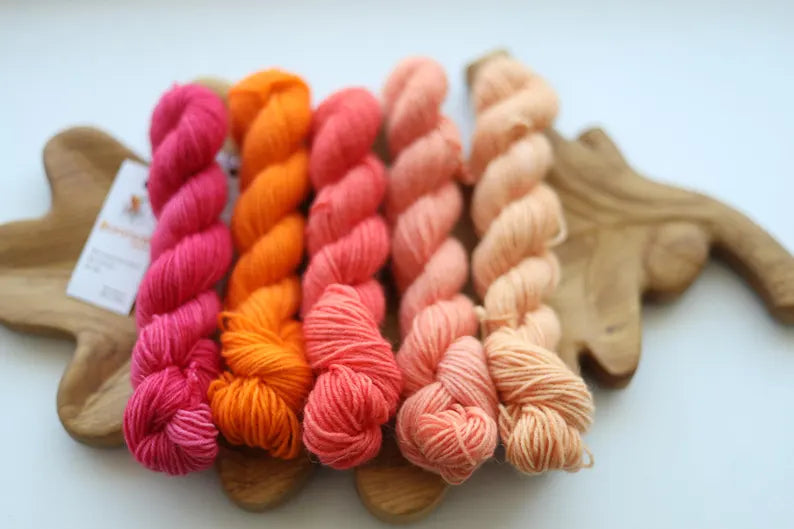 Hand dyed mini skein set with five coordinating sock yarn minis in pink, coral, peach and cream shades for fade knitting and colorwork projects.