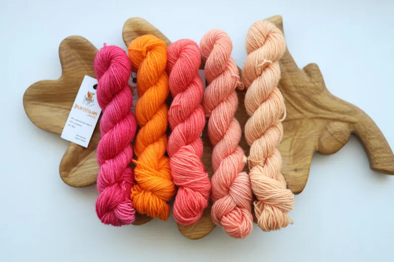 Hand dyed mini skein set with five coordinating sock yarn minis in pink, coral, peach and cream shades for fade knitting and colorwork projects.