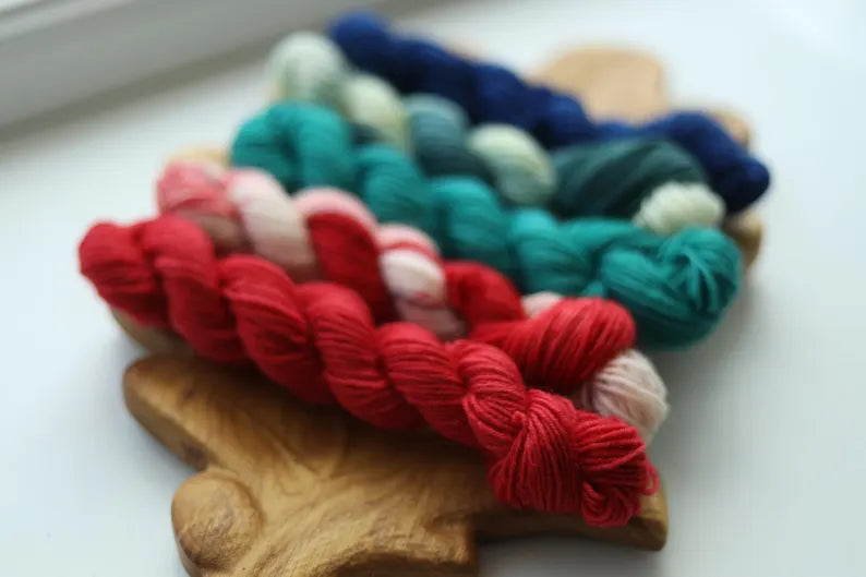 Hand dyed Christmas mini skein set with five festive sock yarn minis in red, candy cane, teal, evergreen and deep blue.