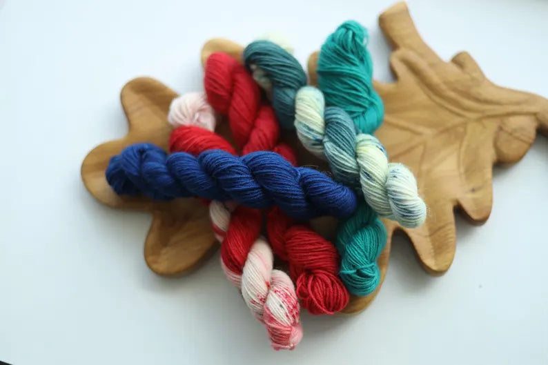 Hand dyed Christmas mini skein set with five festive sock yarn minis in red, candy cane, teal, evergreen and deep blue.