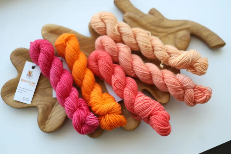 Hand dyed mini skein set with five coordinating sock yarn minis in pink, coral, peach and cream shades for fade knitting and colorwork projects.