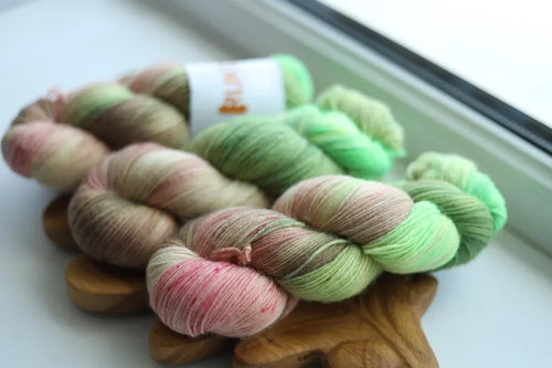 Hand dyed sock yarn in fresh green, blush pink, cream and delicate speckles inspired by blooming apple blossoms, fingering weight wool nylon knitting yarn.