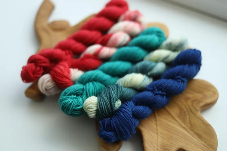 Hand dyed Christmas mini skein set with five festive sock yarn minis in red, candy cane, teal, evergreen and deep blue.