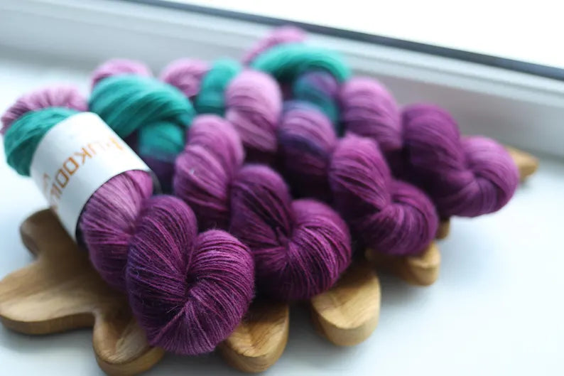 Purple and green hand dyed sock yarn with lavender shades, 4-ply fingering weight yarn for knitting socks.