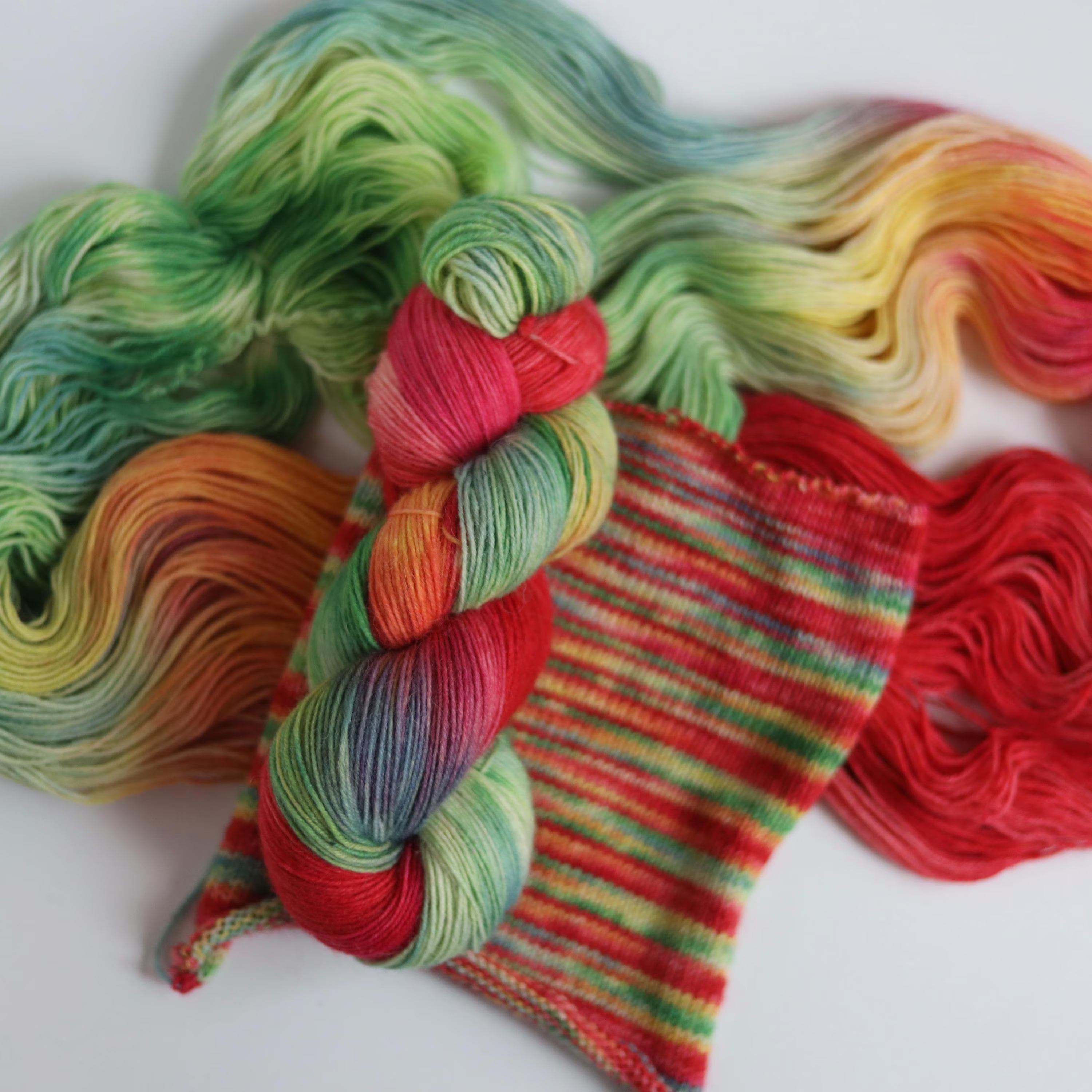 Bright hand dyed sock yarn in watermelon pink, lime green, aqua blue and sunset orange tones on superwash wool nylon fingering weight base.