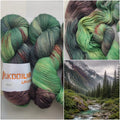 Hand dyed forest green sock yarn with earthy brown and moss tones inspired by mountain landscapes and nature.