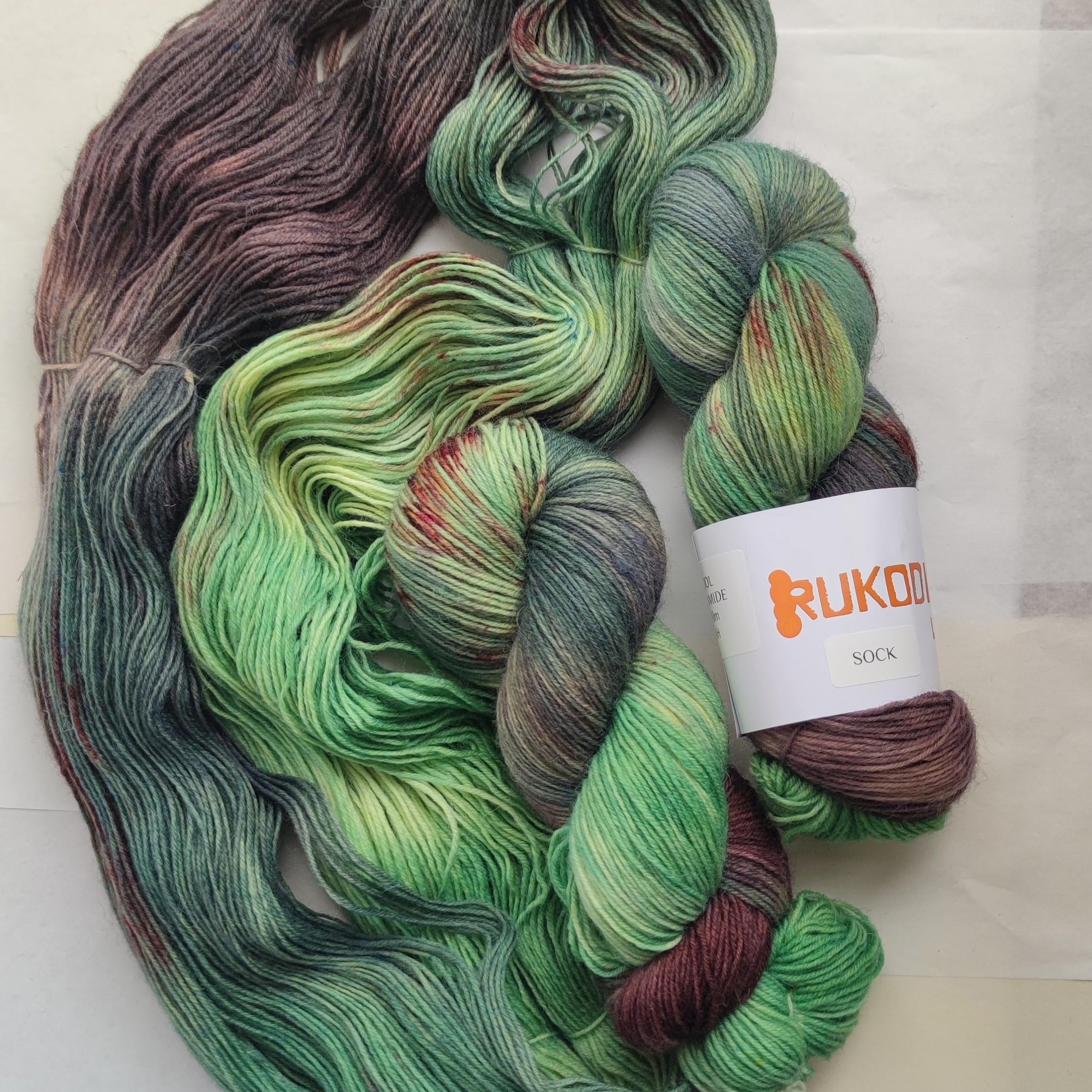 Hand dyed forest green sock yarn with earthy brown and moss tones inspired by mountain landscapes and nature.